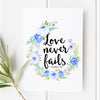 Love Never Fails Christmas print featuring 1 Corinthians 13:8 in elegant script, surrounded by blue and white floral wreath. Inspirational Christian gift for holiday decor.